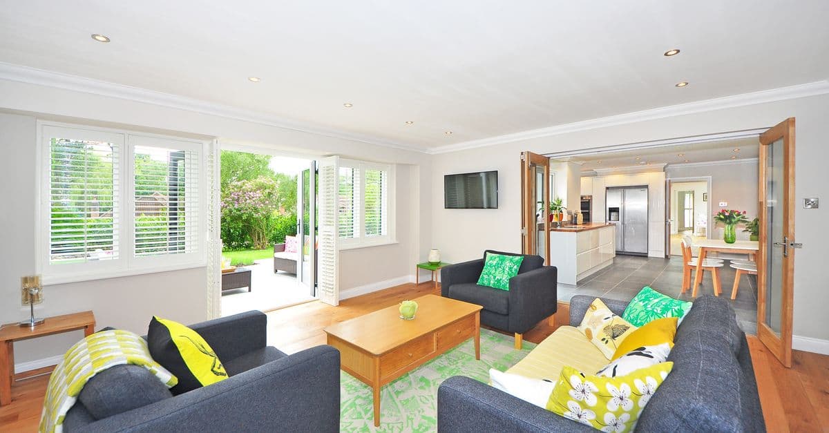 Modern living room with open plan kitchen and garden view, bright and airy ambiance.